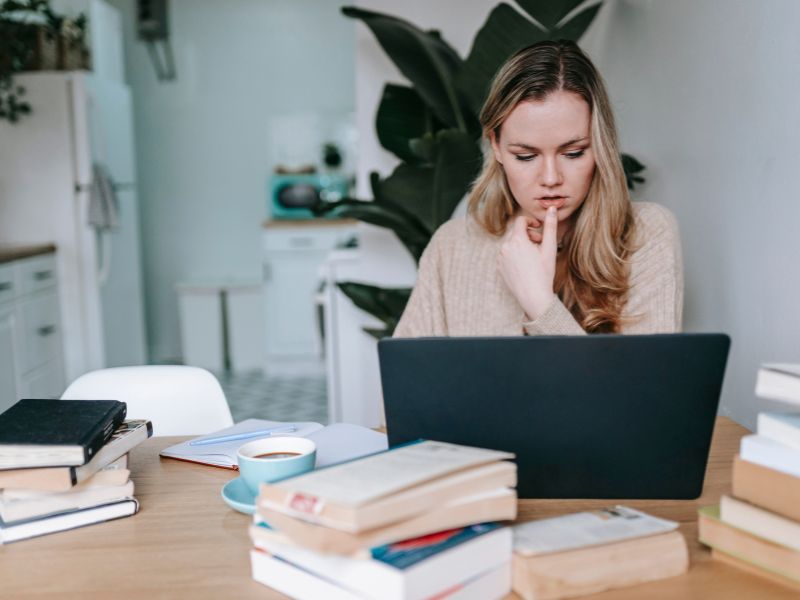 ragazza studia al computer con libri sopra al tavolo